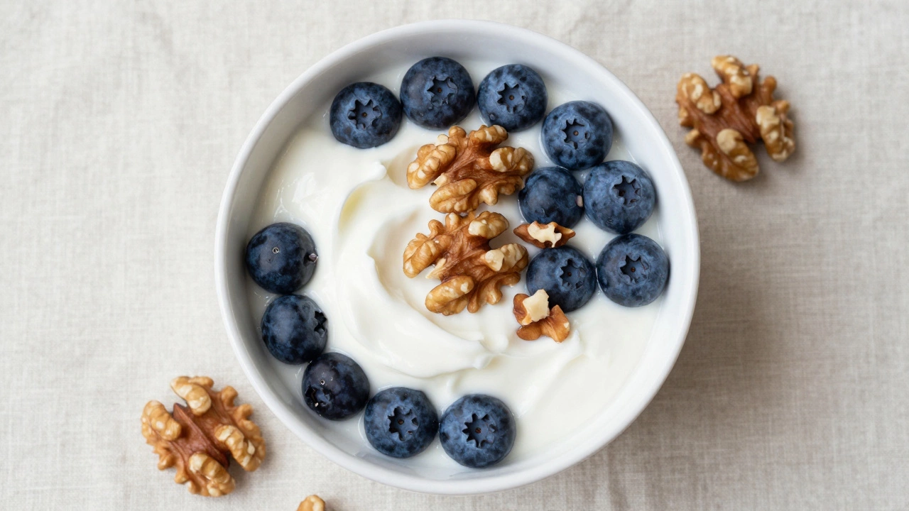 Greek yogurt topped with fresh blueberries and walnuts in a white bowl.